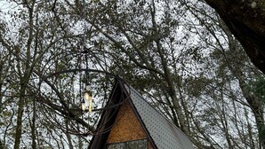 Una baita di legno triangolare chiamata "Casa Torni", con tetto nero, una porta centrale e due finestre.