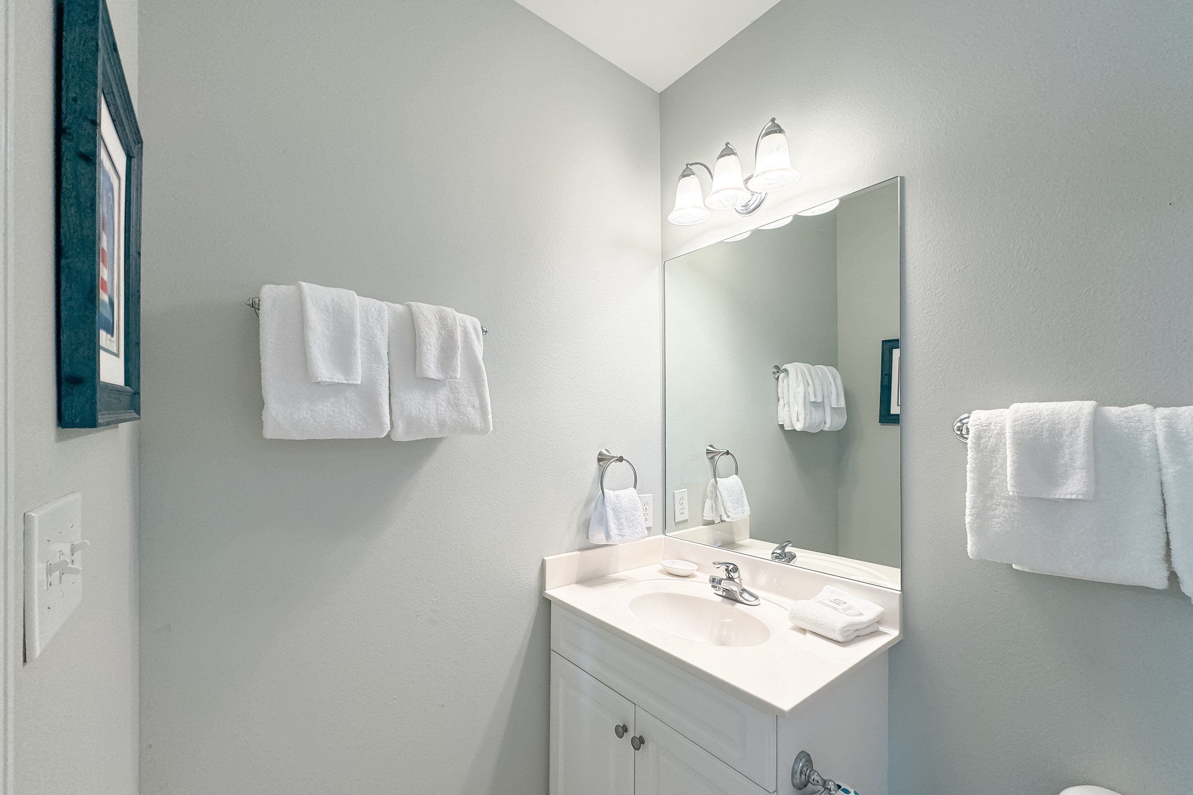 A bathroom with a white sink, mirror, and two towels hanging on the wall.