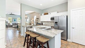 A modern kitchen with a large island, stainless steel appliances, and a dining area with a sofa and chairs. - PRIVATE HOME, QUIET AREA, PERFECT GETAWAY (Gulf Shores)