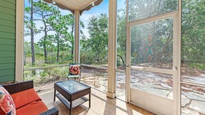 A covered patio with wicker furniture and a glass table, overlooking a forested area. - PRIVATE HOME, QUIET AREA, PERFECT GETAWAY (Gulf Shores)