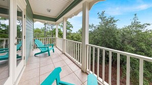 A covered porch with teal chairs and a white railing, overlooking a wooded area. - PRIVATE HOME, QUIET AREA, PERFECT GETAWAY (Gulf Shores)