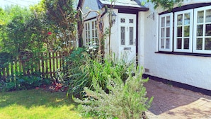A house with a white exterior, a small garden, and a wooden fence.