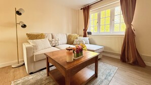 A living room with a sofa, a wooden coffee table, a floor lamp, and a window with curtains.