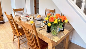A dining table set with plates, glasses, and a vase of flowers.