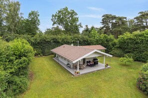 A single-story house with a covered porch, a barbecue grill, and a lawn.