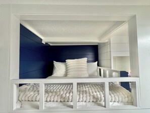 Una cama litera con estructura blanca y cabecera azul oscuro.