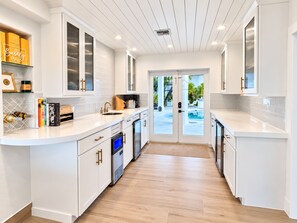 A modern kitchen with white cabinetry, a built-in oven, and a large window overlooking a pool area.