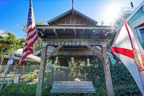 Estructura de madera con la leyenda 'ADVENTURE GOLF', una bandera estadounidense y una bandera estatal.