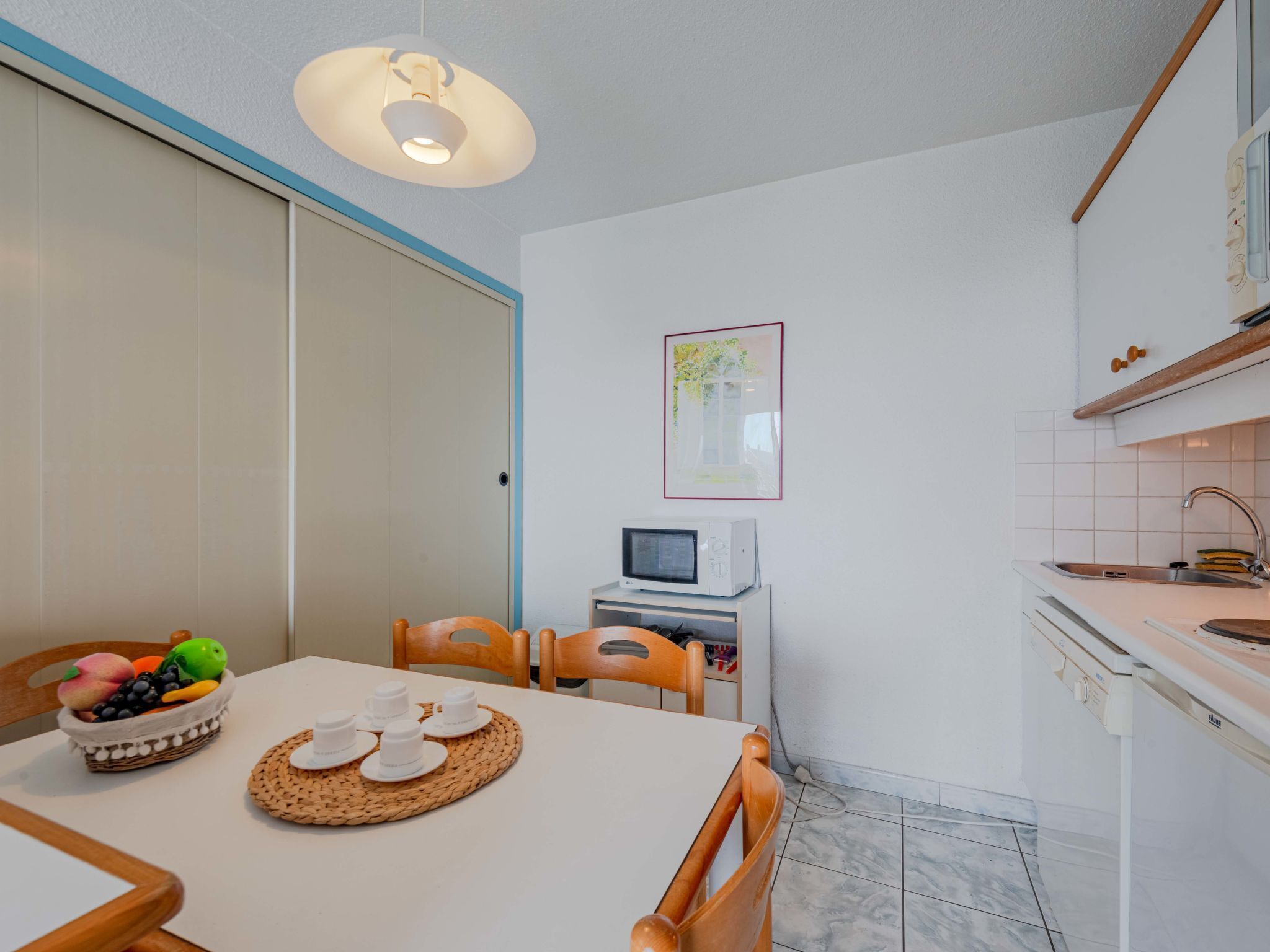A compact kitchen with a microwave, a small sink, and a dining area with a table set for two.