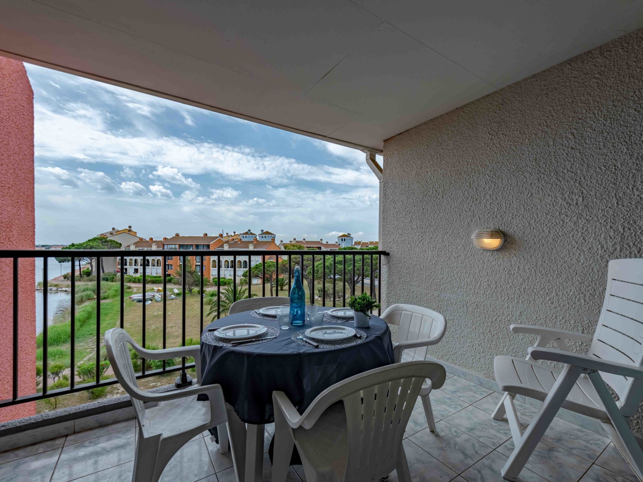 A balcony with a table set for two, overlooking a river and buildings.