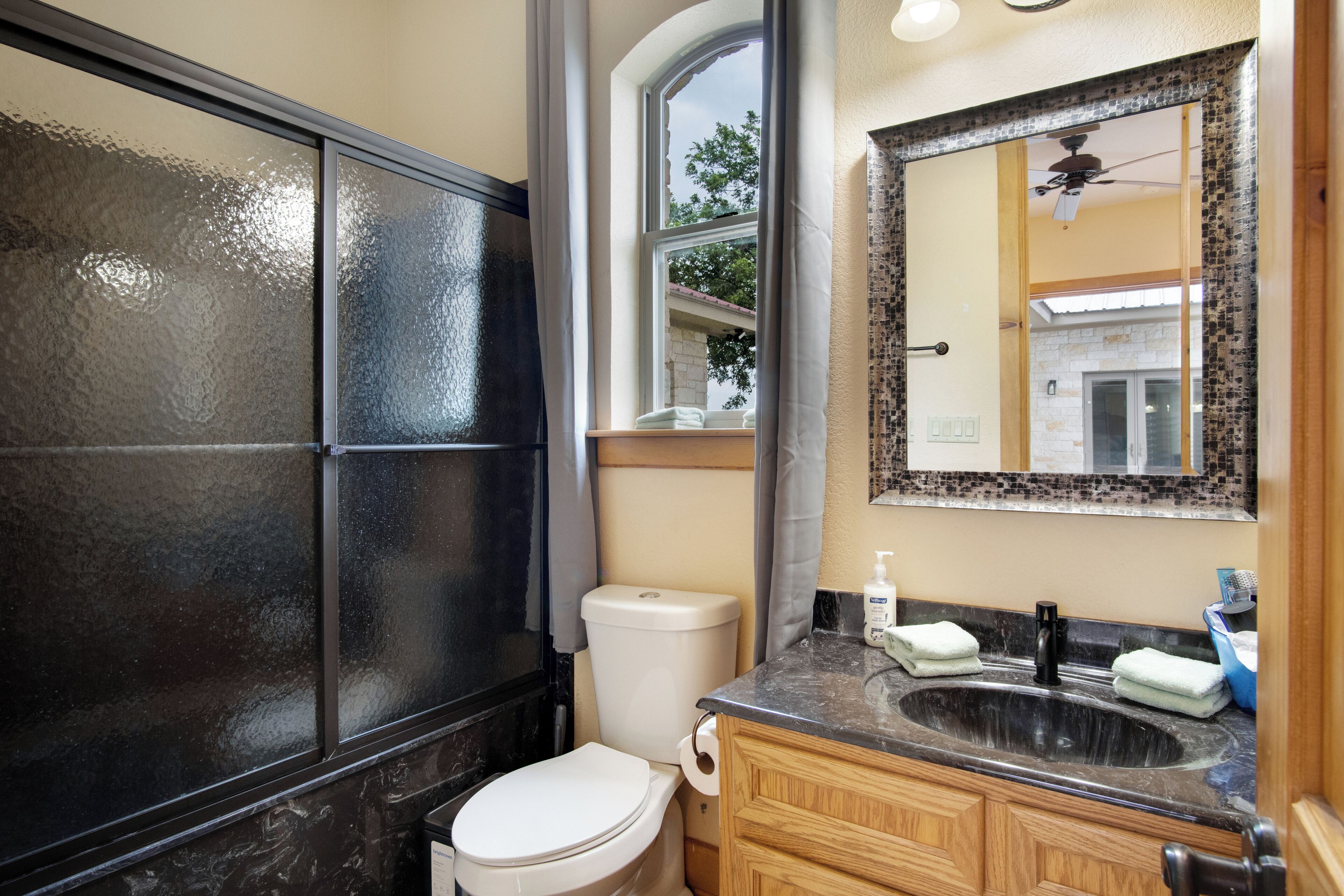 A bathroom with a toilet, sink, vanity, and a large mirror.