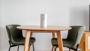 A round wooden table with two green upholstered chairs. A white object is placed on the table. - Blueground | ID97, Basel-Vorstaedte, Washer-Dryer (Basel)
