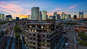 A multi-story building with a modern design, featuring balconies and a rooftop terrace.