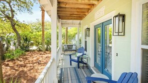 A covered porch with a wooden ceiling, blue chairs, and a table.