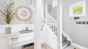 A staircase with white railings, a mirror, and a decorative wall piece.