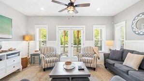 A living room with a ceiling fan, two striped armchairs, a dark sofa, a coffee table, and a large mirror.