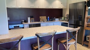 A modern kitchen with a large island, stainless steel appliances, and bar stools.