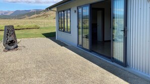 A building with large sliding glass doors, a gravel driveway, and a view of a mountainous landscape.