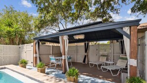 Un espacio al aire libre techado con piscina, sillas de descanso y plantas en macetas.