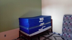 A stack of blue mattresses on a wooden stand in a room with green and white walls. - Santa Maria da Serra Farm, sleeps up to 2 people (Maria vitoria 1 Dois Córregos)