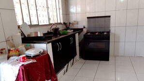 A kitchen with white tiled walls, a black stove, and a window with decorative bars. - Santa Maria da Serra Farm, sleeps up to 2 people (Maria vitoria 1 Dois Córregos)