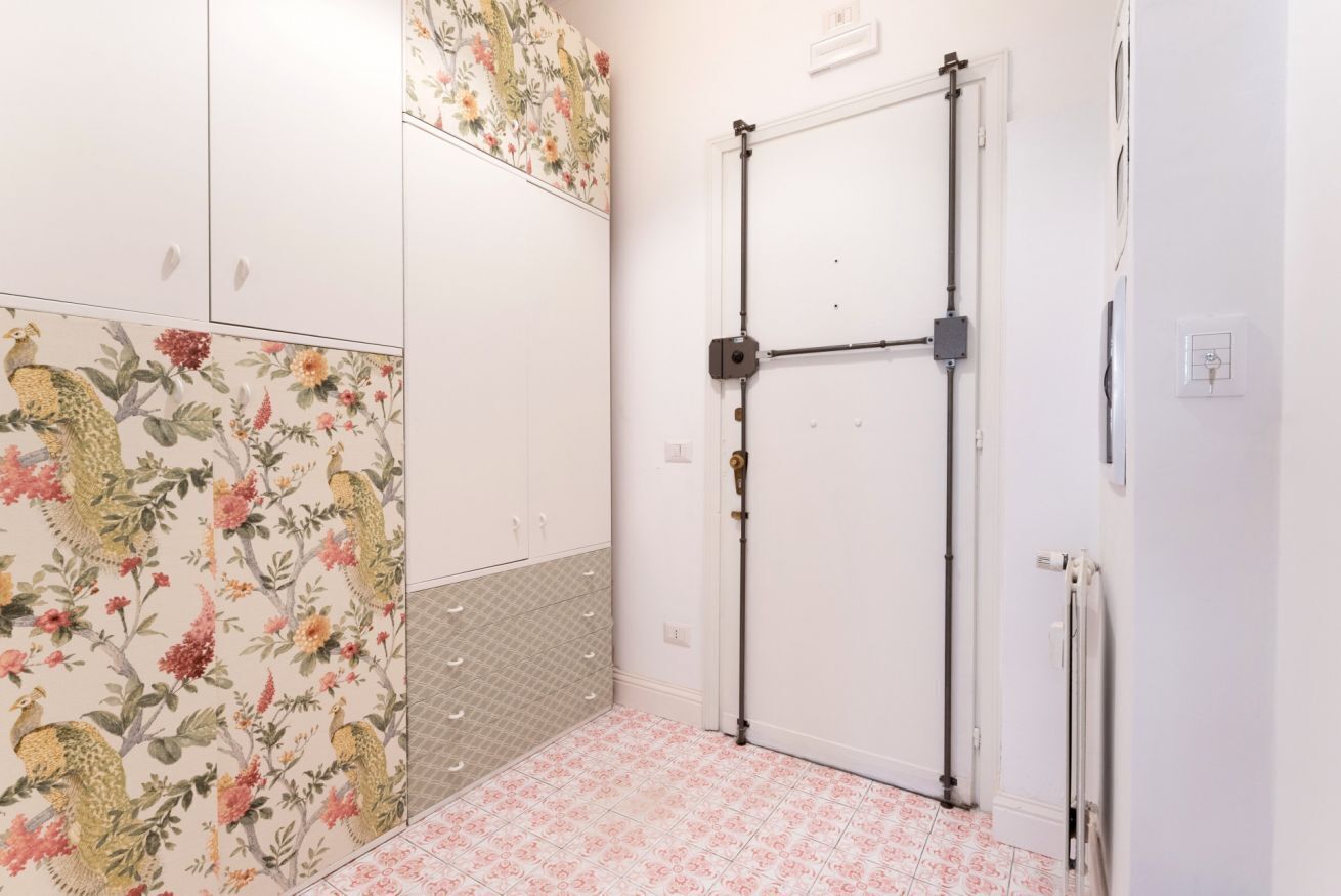 A room with floral wallpaper, a white door, and a radiator.