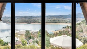 A view from a window overlooking a lake, hills, and a bridge.