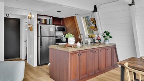 A kitchen with a wooden island, stainless steel appliances, and a window with plants.
