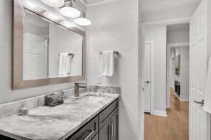 Une salle de bain avec un lavabo en marbre, un grand miroir et un porte-serviettes.