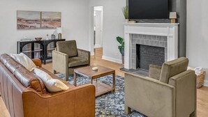 Una sala de estar moderna con un sofá, sillones, una mesita de centro y una chimenea.