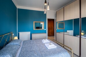 A bedroom with a bed, bedside tables, a mirror, and a wardrobe.