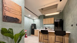 A modern kitchen with a central island, bar stools, a refrigerator, and a water dispenser. - A Day A Room (Taichung)
