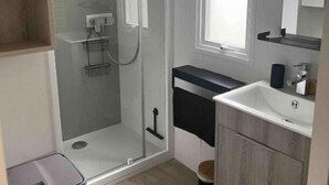 Un baño moderno con cabina de ducha de vidrio, un lavabo con espejo y una ventana que proporciona luz natural.