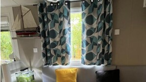 Un interior acogedor con un sofá, cojines, una mesita y una ventana con cortinas.