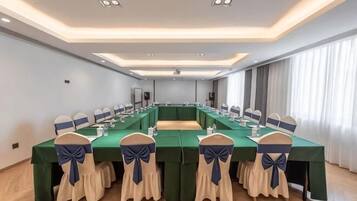 A conference room with a long table, chairs with blue sashes, and a modern ceiling design.