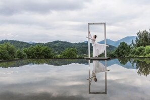Iemand danst voor een reflecterend oppervlak, met een berglandschap op de achtergrond.