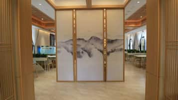 A hotel lobby with a traditional Asian-style partition, a reception desk, and a seating area.