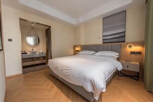 A modern bedroom with a large bed, bedside tables, a mirror, and a painting on the wall.