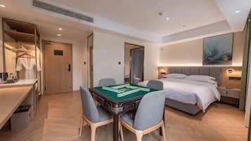 A hotel room with a bed, bedside table, lamp, and a table with a board game.