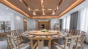 A conference room with a round table, wooden chairs, and a modern ceiling design. - Nanxi River Lion Crag Hotel (Yongjia)