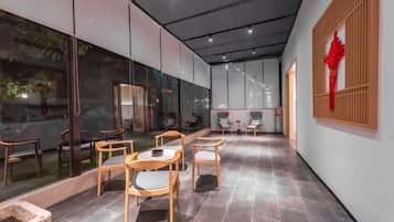 Un interior modern amb una zona de menjador que inclou taules i cadires, un finestral amb vistes i una peça decorativa a la paret.