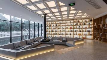 A modern interior with a seating area, a wall of framed items, and large windows.