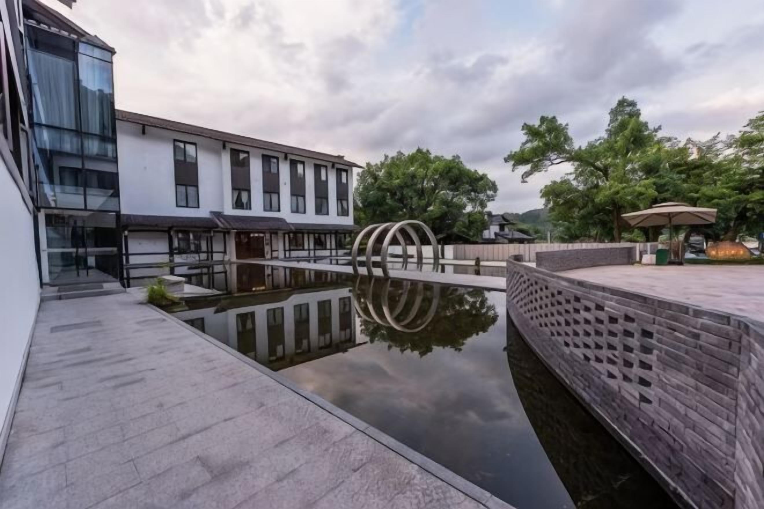 Un patio con una fuente de agua reflectante, un muro de ladrillo y un edificio moderno con amplias ventanas.