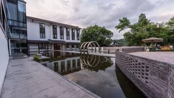 Un patio con una fuente de agua reflectante, un muro de ladrillo y un edificio moderno con amplias ventanas.