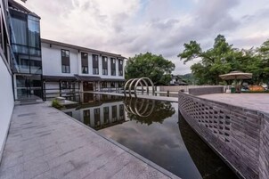 Un patio con una fuente de agua reflectante, un muro de ladrillo y un edificio moderno con amplias ventanas.