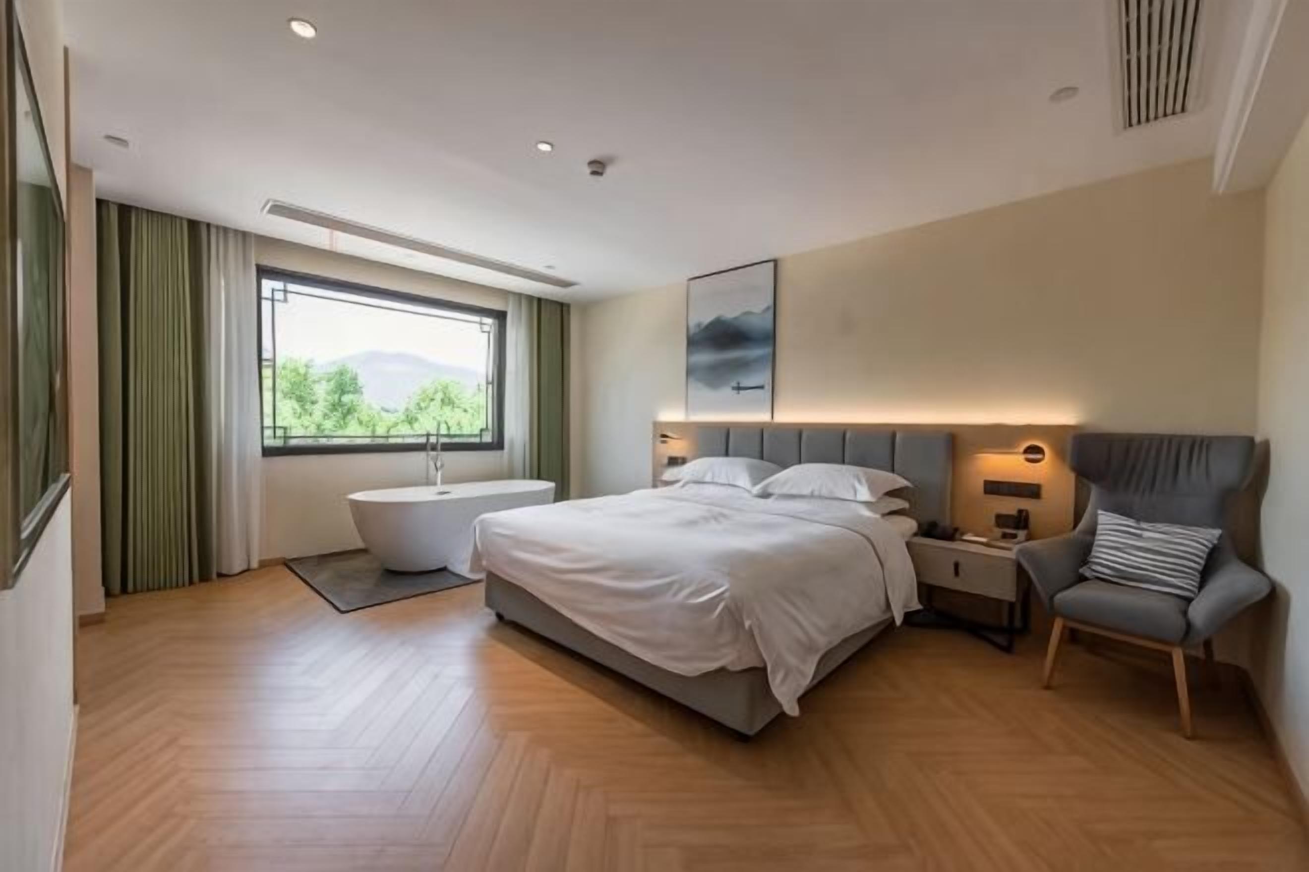 Un dormitorio moderno con una cama grande, un rincón de descanso y vistas al exterior.