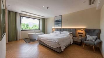 Un dormitorio moderno con una cama grande, un rincón de descanso y vistas al exterior.