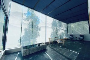 A modern interior with a large window, a stone water feature, and seating.
