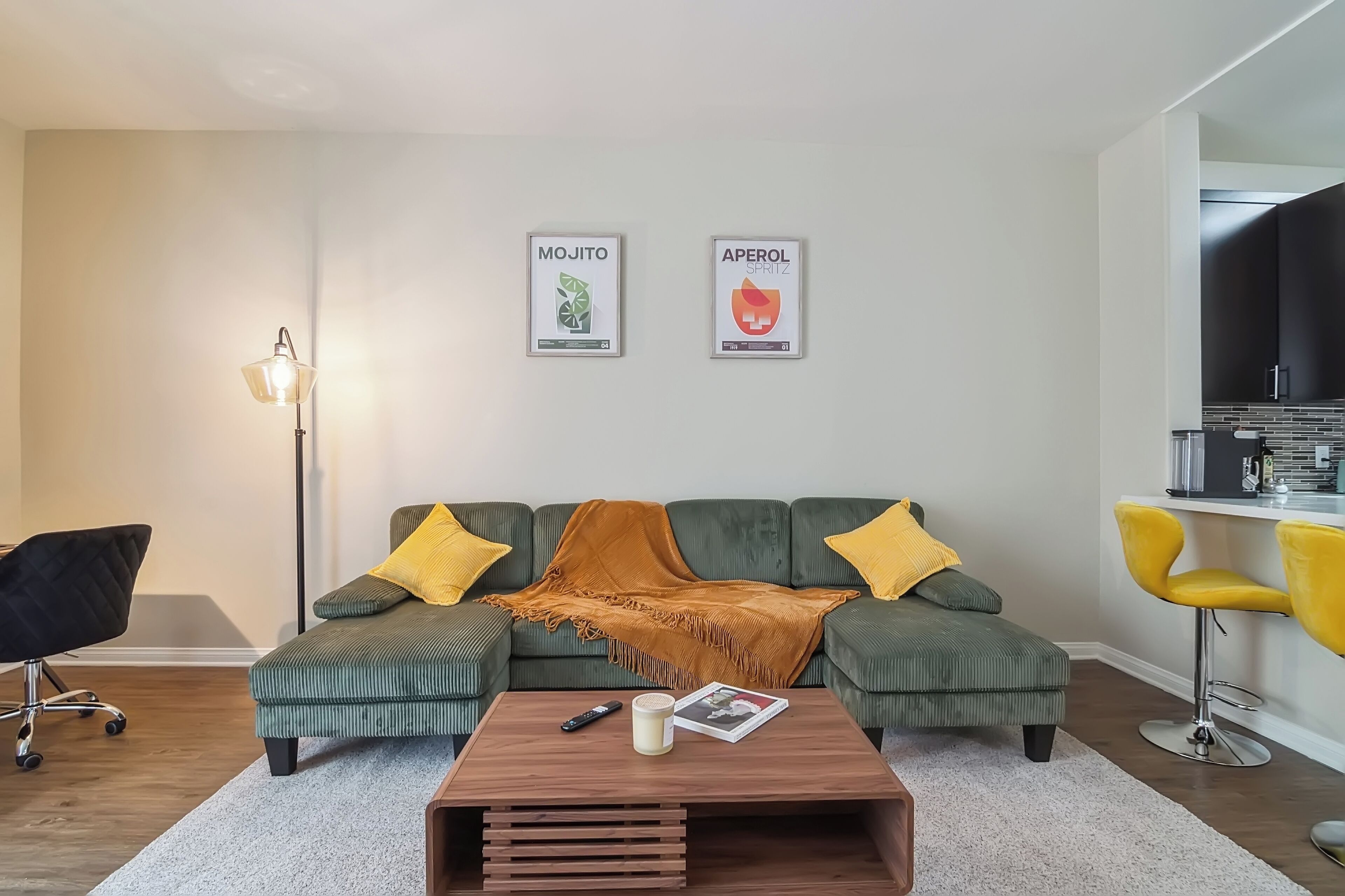 A modern living room with a green sofa, yellow cushions, a wooden coffee table, and a floor lamp.
