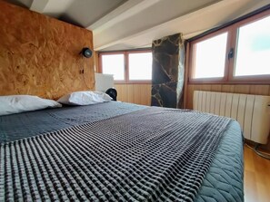 A bed with a patterned bedspread, a wooden headboard, white pillows, and a nightstand with a lamp.